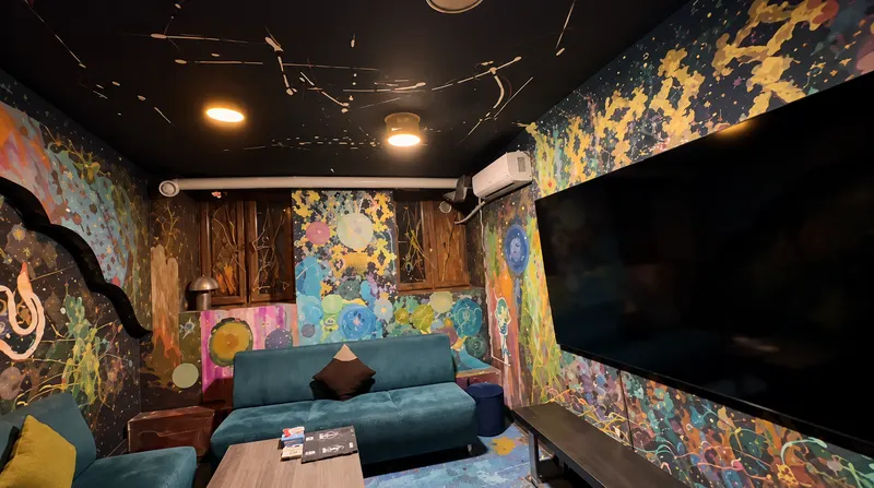 VIP Room 1 — teal sofas under colourful space murals, wall-mounted TV