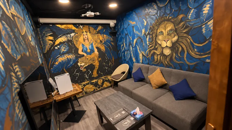 Private room with blue and gold lion and Cleopatra murals, grey sofa and PS5 consoles